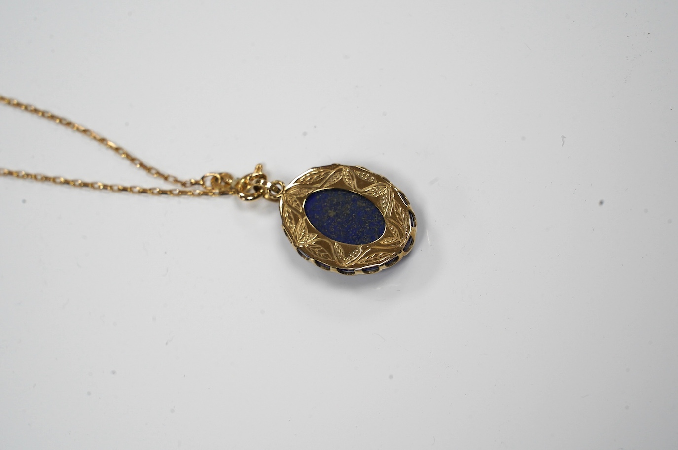 A modern 9ct gold mounted oval lapis lazuli pendant, 25mm, on a 9k fine link chain, 36cm, gross weight 8.2 grams. Condition - fair to good